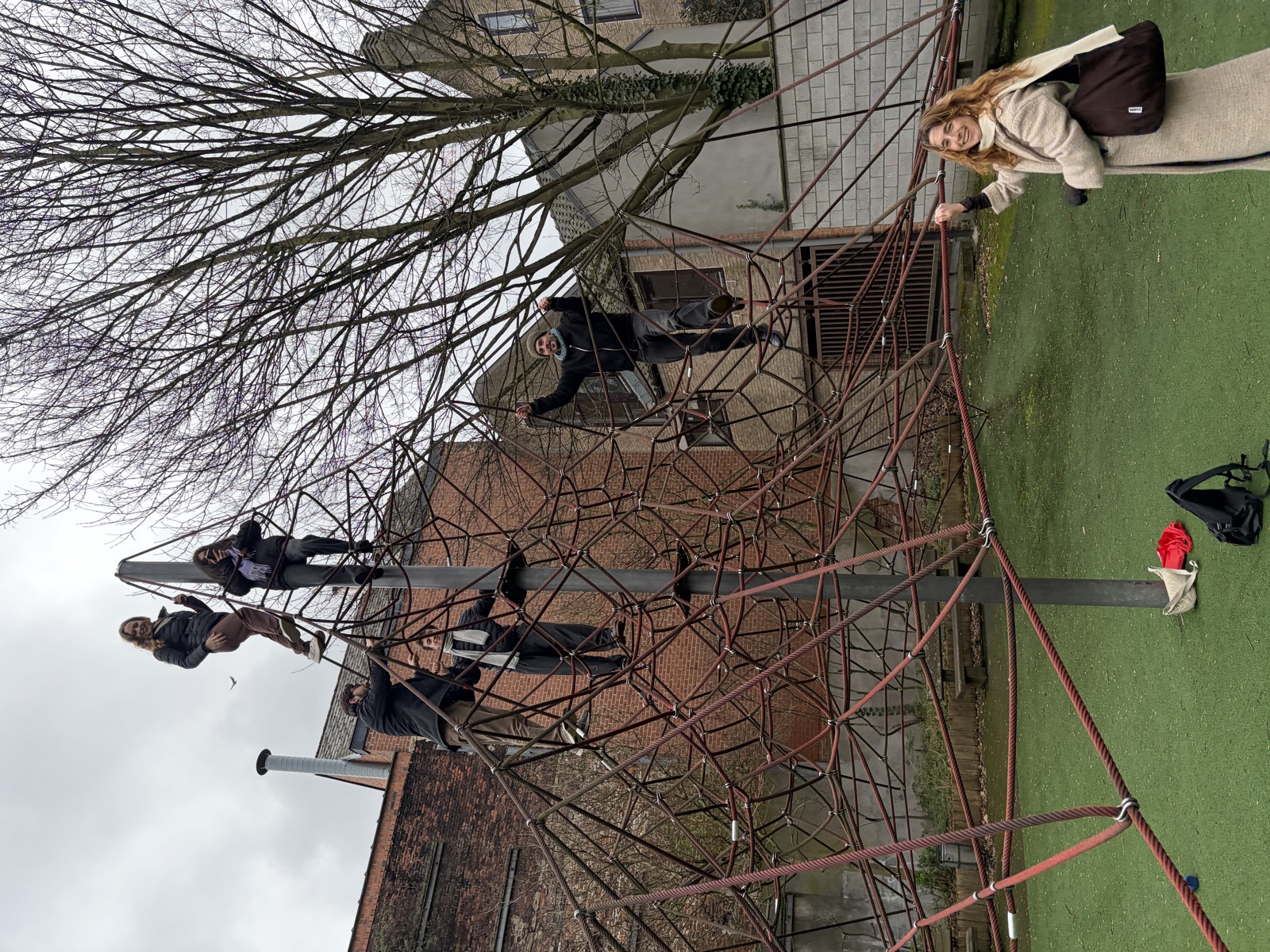 Six people on a red rope climbing frame in an urban playground