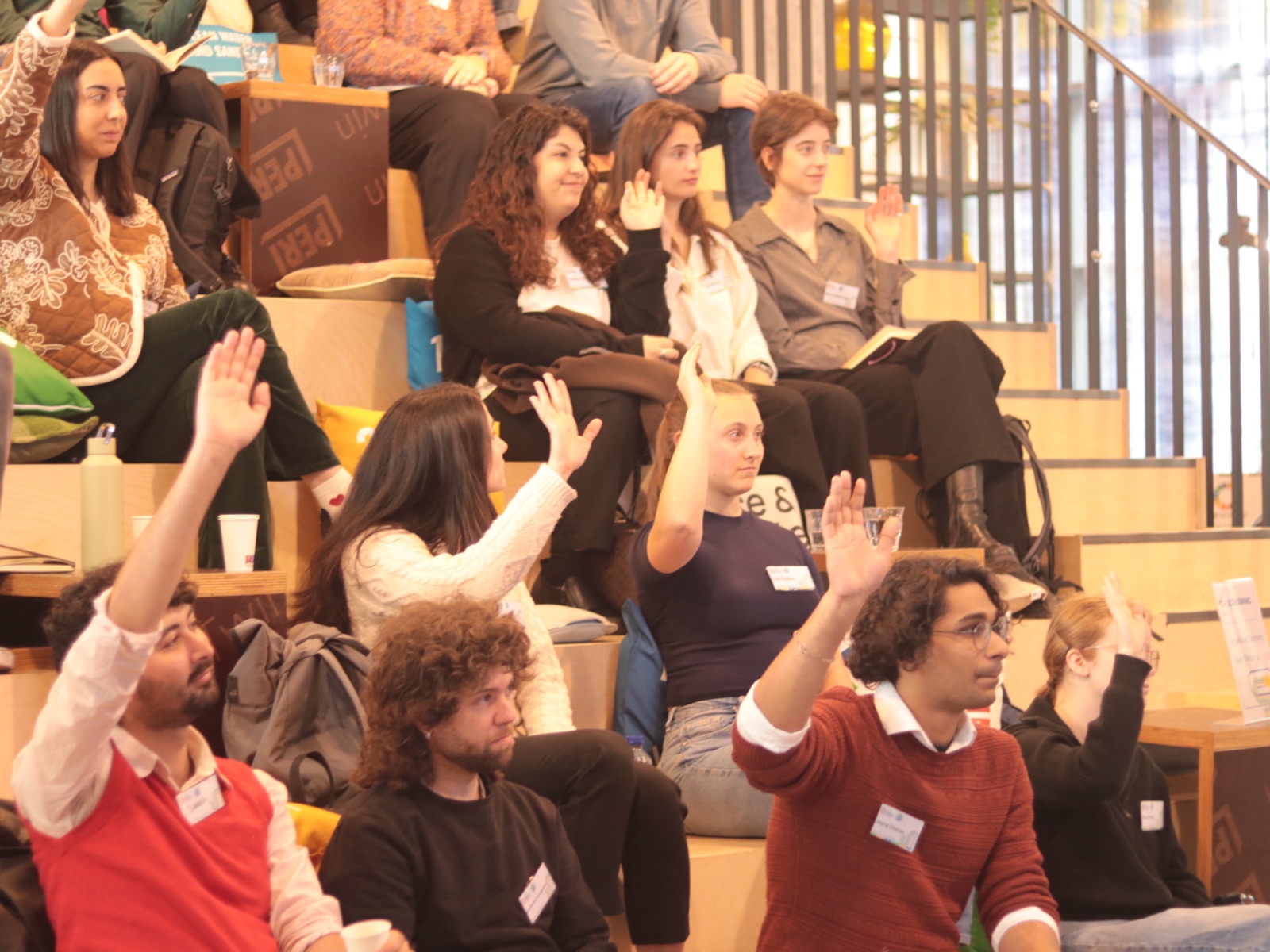 Jayraj raising his hand on tiered wooden seating during a group workshop